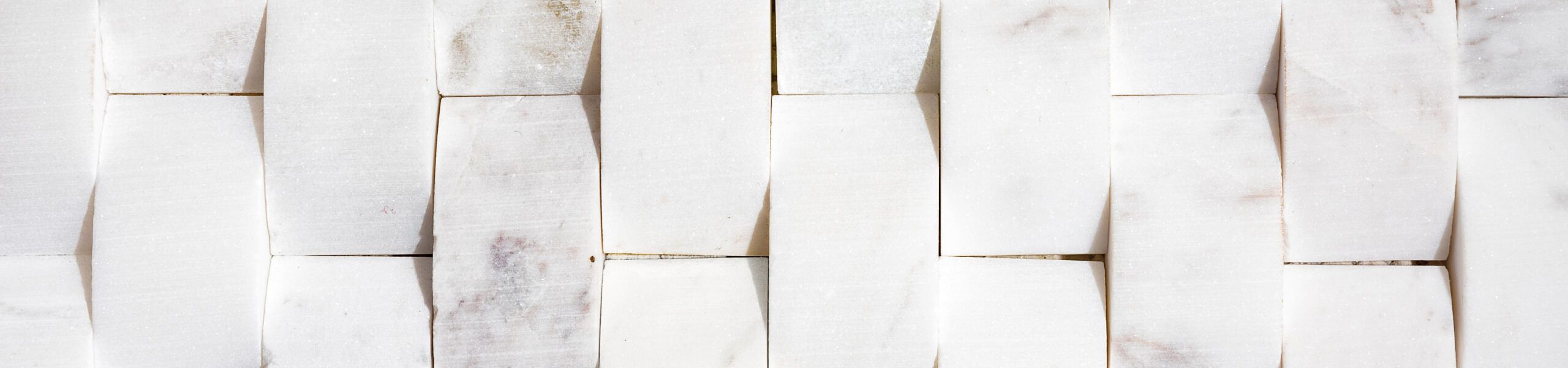 Piastrelle in marmo bianco ad arco per pareti o pavimenti. Piastrella moderna bianca naturale utilizzata per bagni, backsplash di cucina o pareti in evidenza. Piastrella 2x4 curva o bombata verso l'alto, posa piana. Focus selettivo.